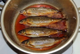 焼き枯らしたアユを鍋に並べて、醤油、ミリン、酒、砂糖を入れれ時間をかけてじっくり煮詰める。